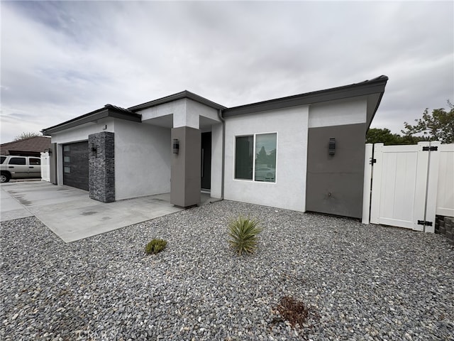 12525 Spring Valley Pkwy, Victorville, CA 92395 - modern home with a gate, fence, concrete driveway, a garage, and stucco siding