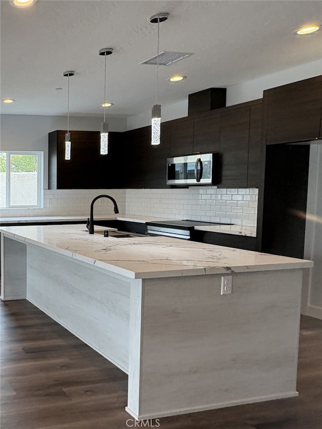 12525 Spring Valley Pkwy, Victorville, CA 92395 - kitchen with backsplash, modern cabinets, stainless steel microwave, a sink, and a kitchen island with sink