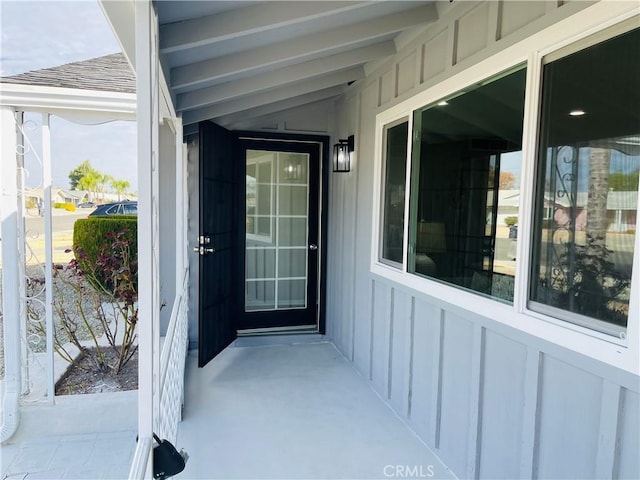 entrance to property with board and batten siding and a shingled roof