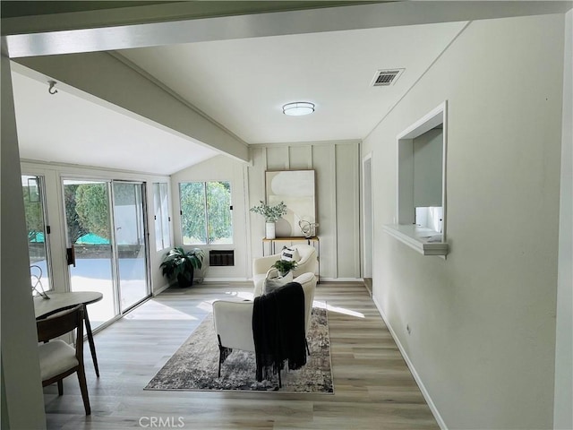 interior space with lofted ceiling with beams, baseboards, visible vents, and light wood-type flooring