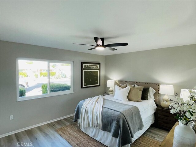bedroom featuring baseboards, wood finished floors, and ceiling fan