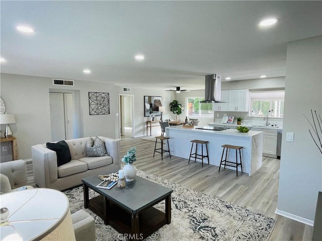 living room with baseboards, recessed lighting, visible vents, and light wood-type flooring