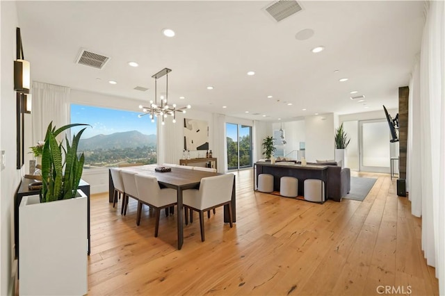 dining room with light wood-type flooring, visible vents, and a chandelier