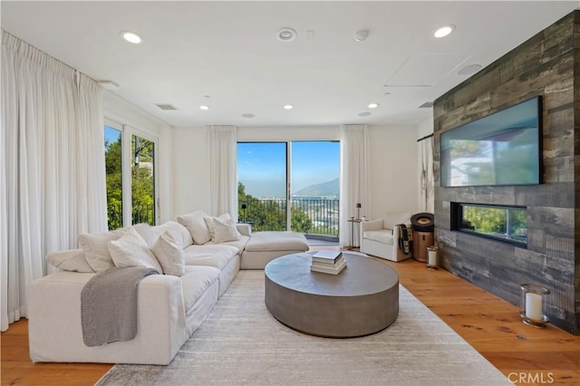 living area featuring a large fireplace, wood finished floors, visible vents, and recessed lighting