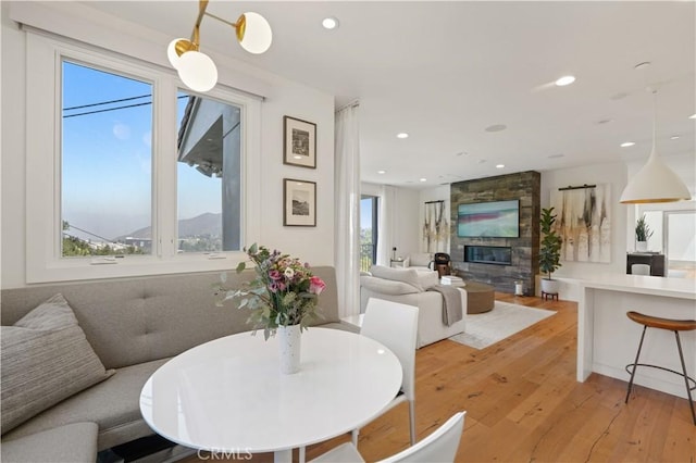 dining area featuring light wood-style flooring, a stone fireplace, and recessed lighting