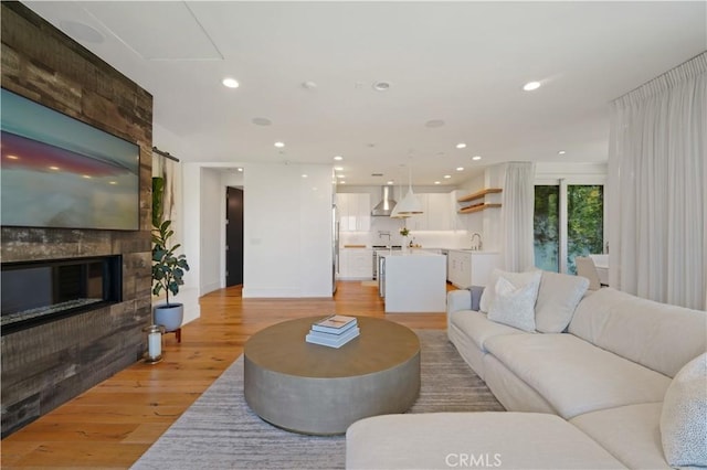living room with a fireplace, light wood-style flooring, and recessed lighting