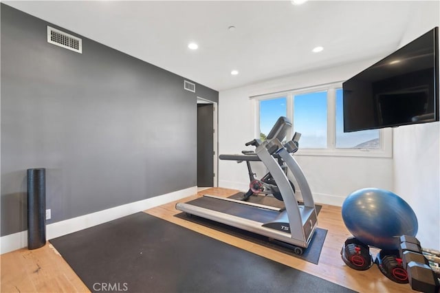 exercise room with baseboards, wood finished floors, visible vents, and recessed lighting