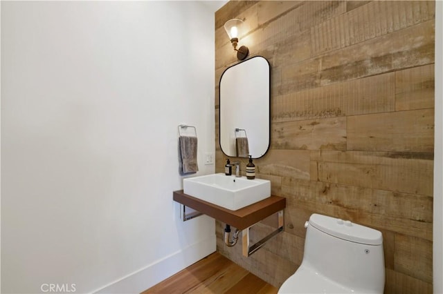 bathroom featuring wood finished floors, toilet, baseboards, and a sink