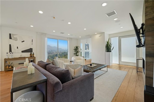 living area featuring recessed lighting, light wood-style floors, and visible vents