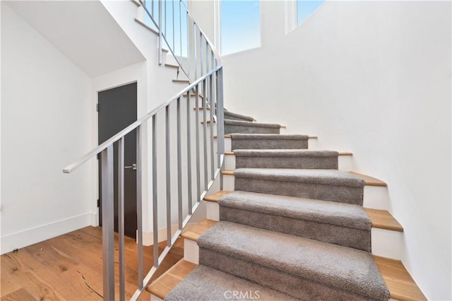 staircase featuring wood finished floors and baseboards