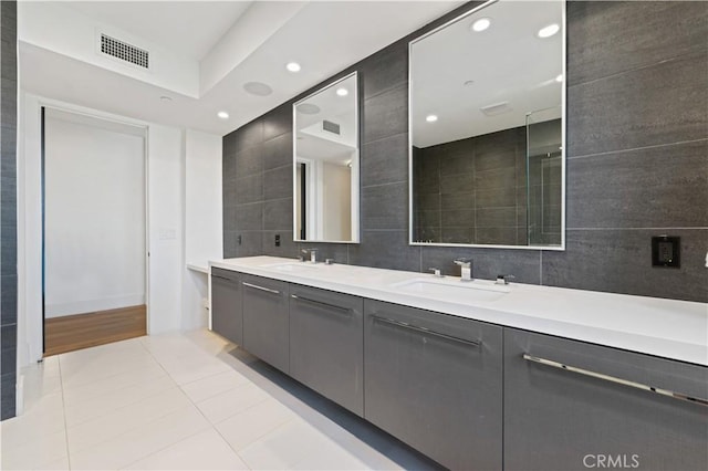 bathroom with tile patterned floors, a sink, double vanity, tile walls, and visible vents