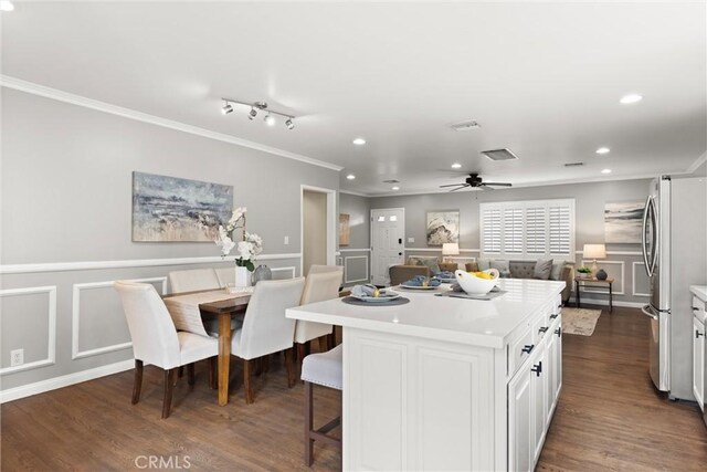 kitchen featuring a decorative wall, crown molding, a breakfast bar area, freestanding refrigerator, and a kitchen island