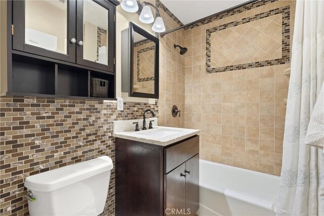 bathroom with tasteful backsplash, vanity, tile walls, shower / tub combo, and toilet