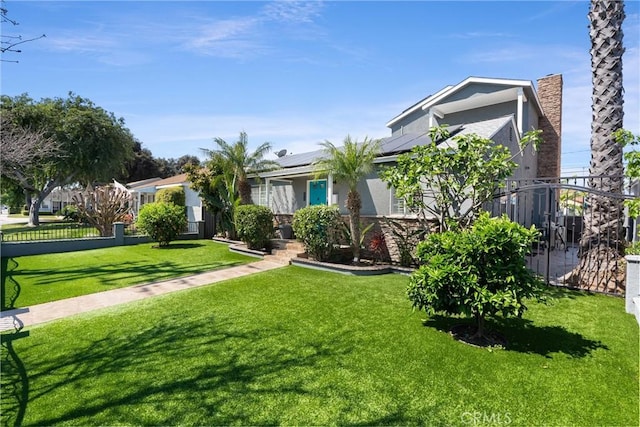 view of front facade featuring roof mounted solar panels, a front yard, stucco siding, and fence