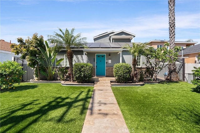 view of front of house with roof mounted solar panels, a front lawn, stucco siding, and fence