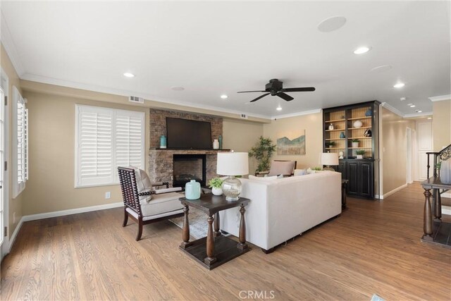 living area featuring recessed lighting, visible vents, a ceiling fan, crown molding, and a fireplace