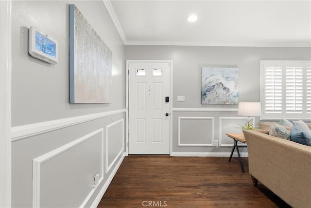 entryway featuring wood finished floors, a decorative wall, crown molding, and a wainscoted wall