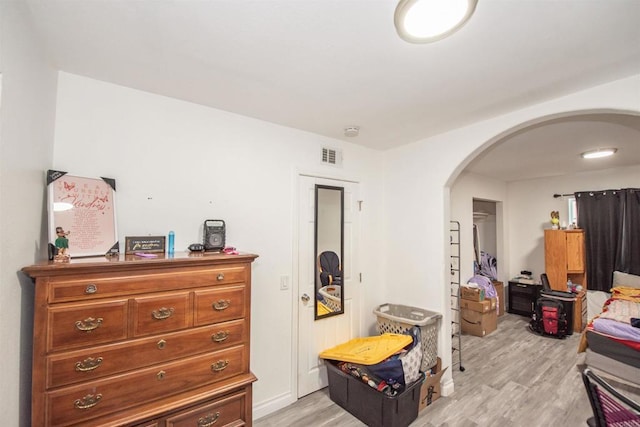 bedroom with visible vents, arched walkways, and light wood-type flooring