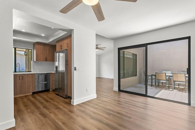 kitchen featuring stainless steel fridge, light countertops, a ceiling fan, wood finished floors, and dishwashing machine