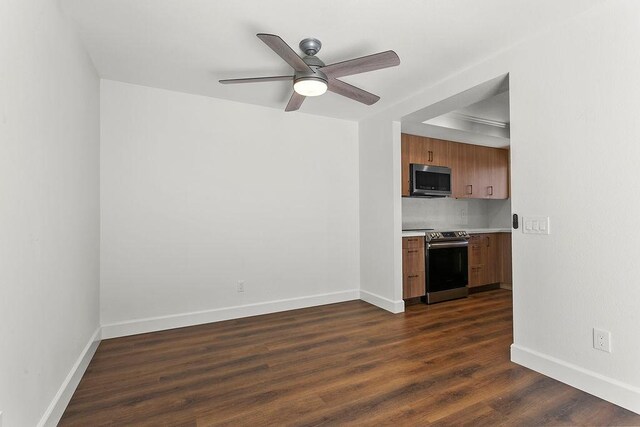 unfurnished living room with ceiling fan, dark wood-style floors, and baseboards
