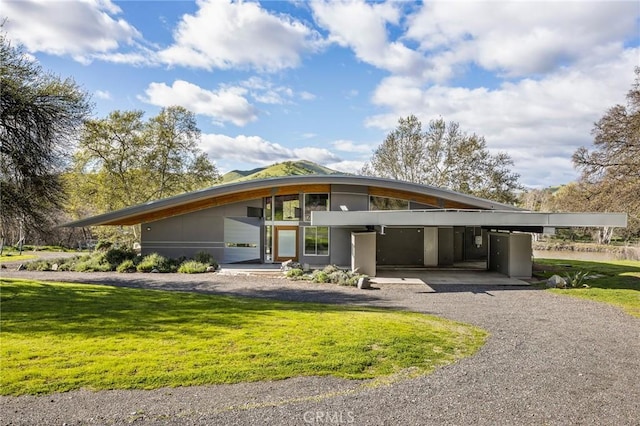 view of front facade featuring gravel driveway, a front yard, and an attached carport