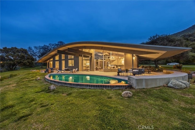 rear view of property with a lawn, an outdoor living space, and a patio area