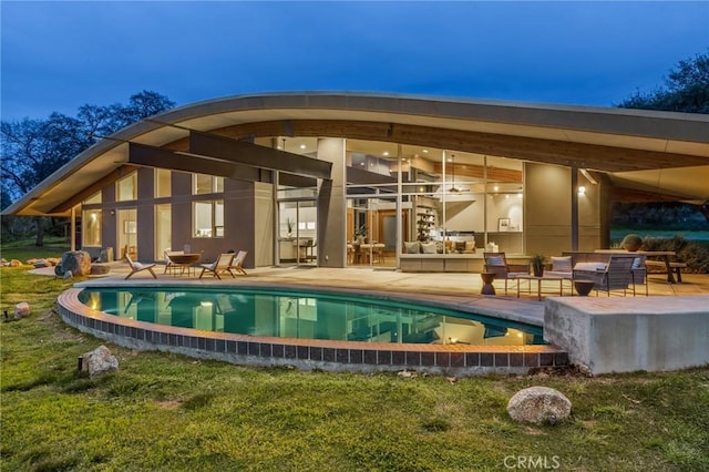 outdoor pool with a patio area, a lawn, and an outdoor living space