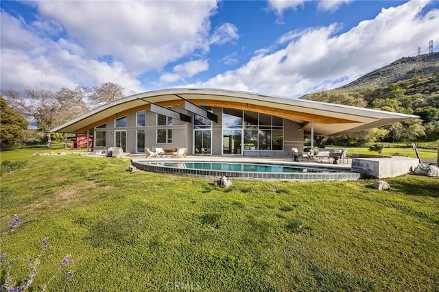 back of house with a patio area, a lawn, and an outdoor pool
