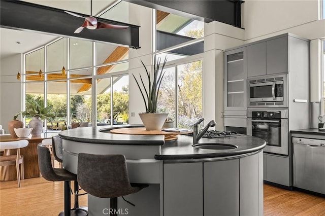 kitchen featuring a sink, dark countertops, light wood-style floors, gray cabinetry, and appliances with stainless steel finishes