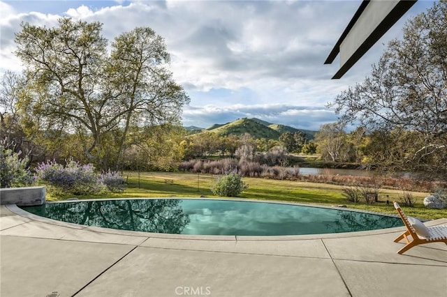outdoor pool featuring a patio area, a yard, and a mountain view