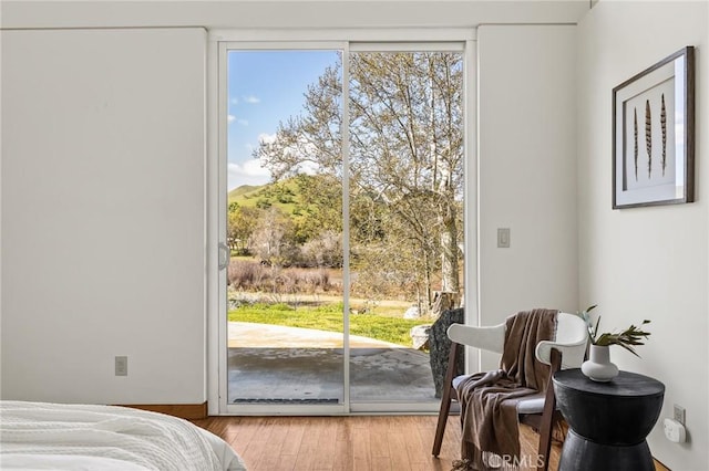 bedroom with multiple windows, access to outside, and wood finished floors