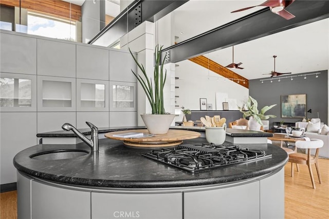 kitchen with white cabinets, light wood-style floors, a ceiling fan, and a sink
