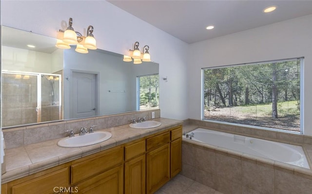 full bathroom featuring double vanity, a garden tub, a stall shower, and a sink