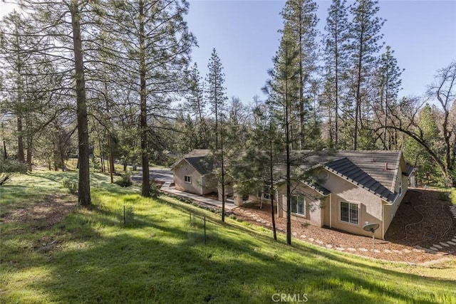 exterior space featuring stucco siding, a tiled roof, and a lawn