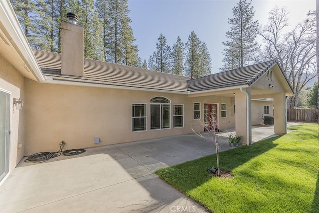 rear view of house featuring stucco siding, a tile roof, and a lawn