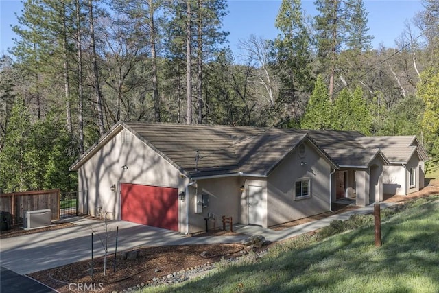 view of outdoor structure with a gate, an attached garage, driveway, and fence