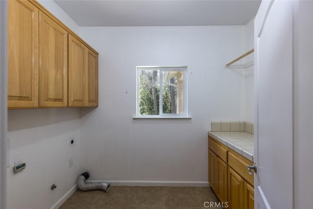 clothes washing area with cabinet space, baseboards, and hookup for an electric dryer