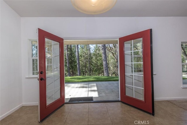 doorway to outside with baseboards, tile patterned flooring, and plenty of natural light