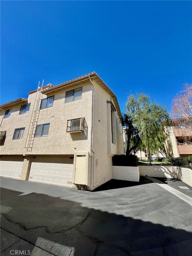 5444 Las Virgenes Rd, Calabasas, CA 91302 - view of side of property featuring an attached garage, a tile roof, and stucco siding