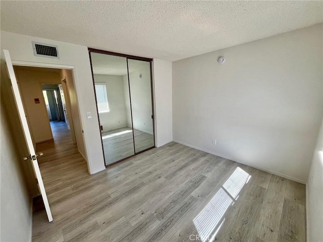 5444 Las Virgenes Rd, Calabasas, CA 91302 - unfurnished bedroom featuring a closet, a textured ceiling, visible vents, and light wood-style flooring