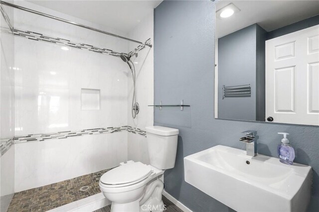 3408 Hathaway Ave Unit 301, Long Beach, CA 90815 - bathroom featuring toilet, a tile shower, a sink, and baseboards