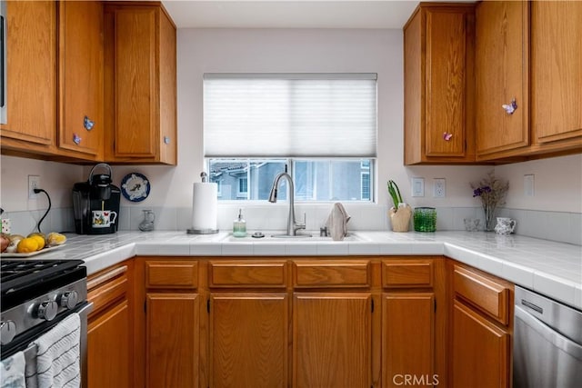 27191 Ryan Dr, Laguna Niguel, CA 92677 - kitchen with light countertops, dishwasher, a sink, gas range oven, and brown cabinetry