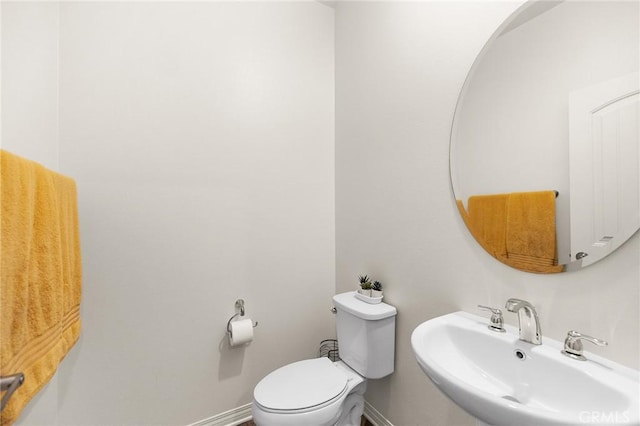 half bath with a sink, toilet, and baseboards