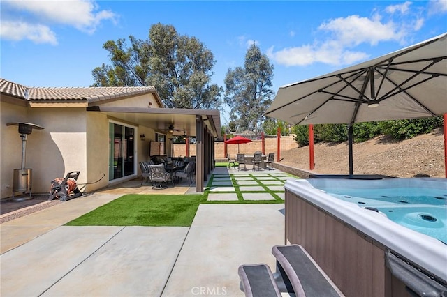 view of yard featuring a hot tub, a ceiling fan, fence, a patio area, and outdoor dining area