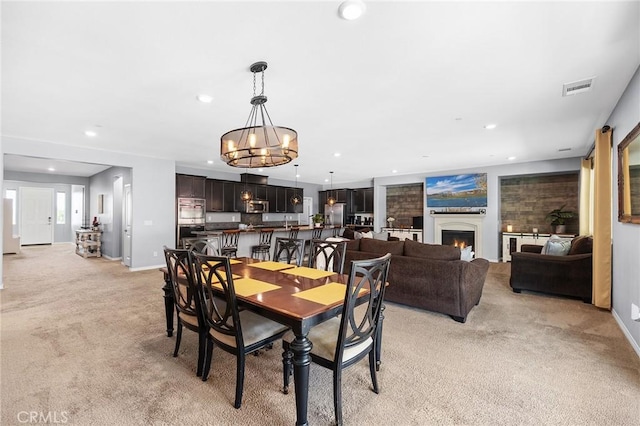 dining room with light colored carpet, a chandelier, baseboards, recessed lighting, and a lit fireplace