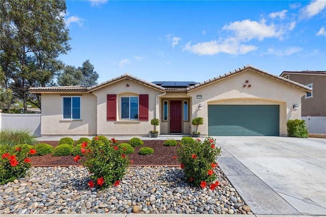mediterranean / spanish home with a tiled roof, fence, an attached garage, and solar panels