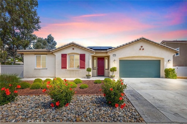 mediterranean / spanish home featuring concrete driveway, fence, solar panels, and a garage