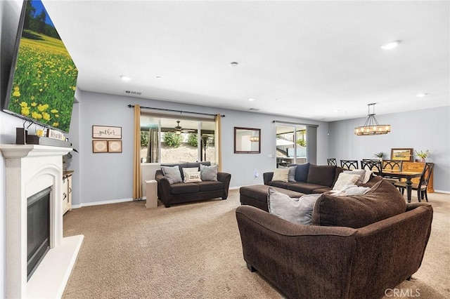 carpeted living room featuring recessed lighting, a chandelier, a fireplace with raised hearth, and baseboards