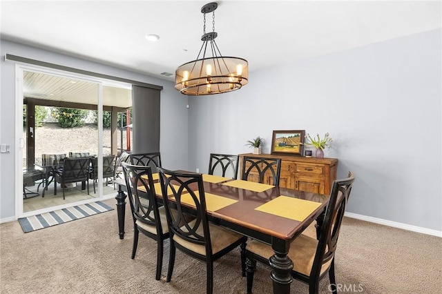 dining space featuring carpet floors, a chandelier, and baseboards
