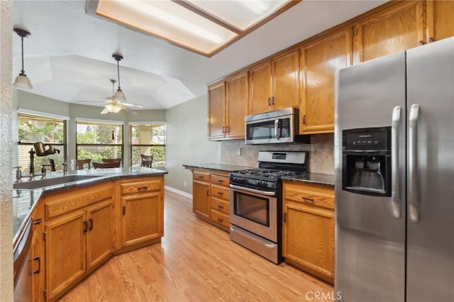 689 E Pintail Cir, Fresno, CA 93730 - kitchen featuring a tray ceiling, a sink, dark countertops, stainless steel appliances, and light wood-type flooring